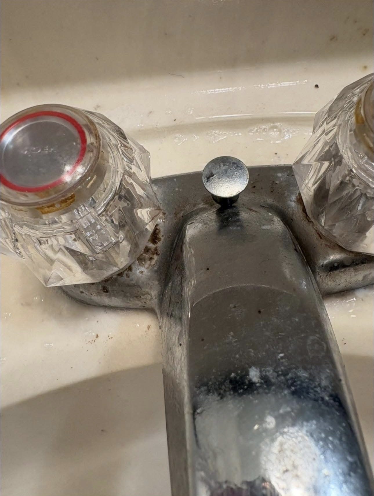 Bathroom faucet before cleaning, covered in hard water buildup