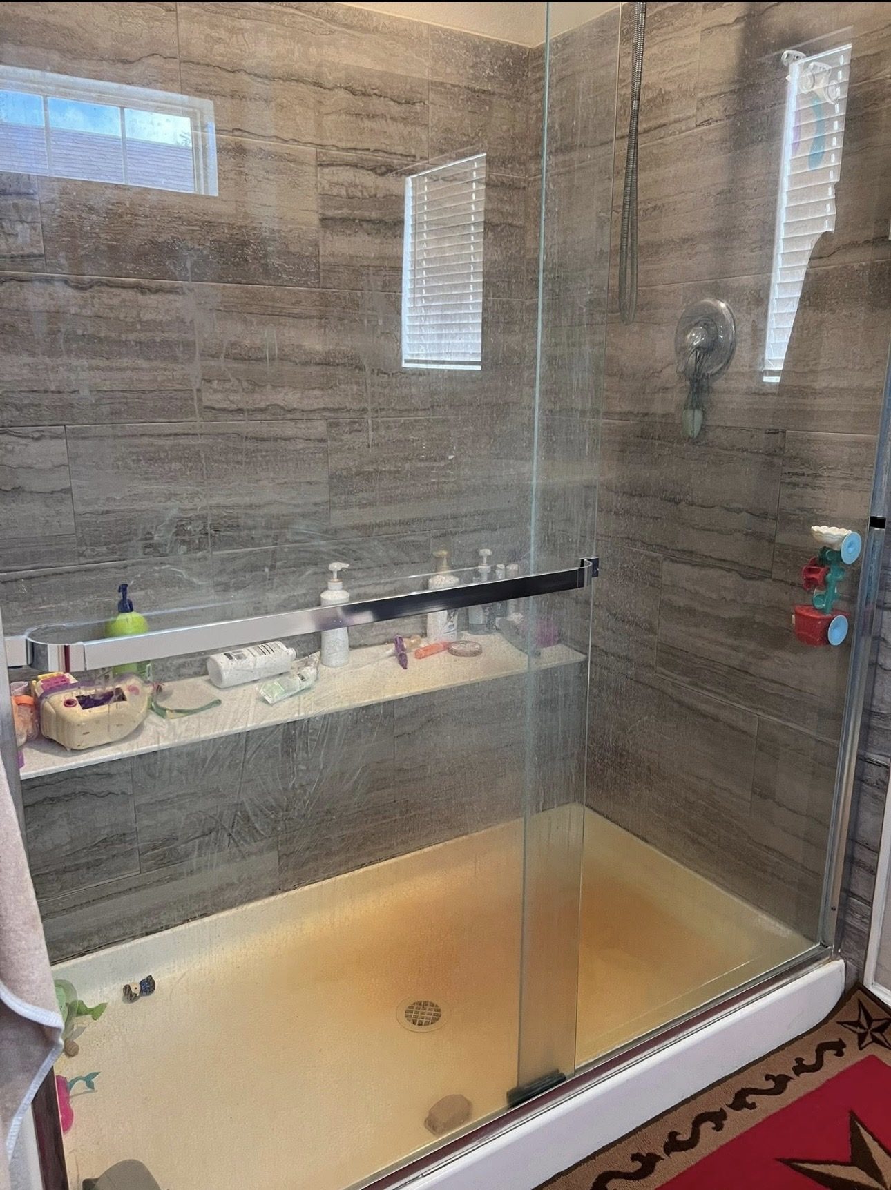 Glass shower enclosure before cleaning, stained floor